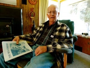 Art Hammer sits in his living room with a booklet of the 1946 shipwreck he was on. Photo/Angela Denning
