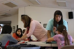 Avery Herrman-Sakamoto (right) and Ronelle Beardslee (left) assist with making headdresses  