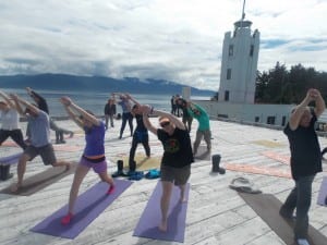 Cruise ship tourists practice yoga in front of the backdrop of Five Finger Lighthouse.(Joe Sykes)