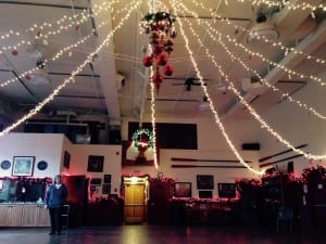 Sally Dwyer stands underneath Christmas decorations downstairs at the Sons of Norway hall. Photo/Angela Denning