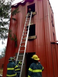 Fire Marshall, Ryan Welde, watches from a third story window as volunteer fire fighters practice raising the ladder. Photo/Angela Denning