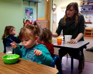Petersburg Children Center teacher, Theressa Phillips, helps toddlers with their breakfast. Photo/Angela Denning