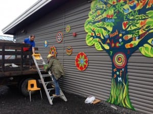 Artist Pia Reilly climbs a ladder to install her paintings on the Rae C. Stedman Elementary. Photo/Angela Denning