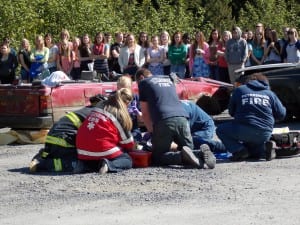Students watch as EMTS try to revive one of the victims in Thursday's mock crash.