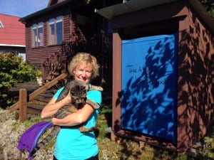 Jo Ann Day hold her cat, Bella, next to her lending library. Photo/Angela Denning