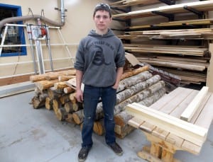 PHS sophomore, Sebastian Davis, stands near alder logs he's using to make a lob cabin dog house. Photo/Angela Denning