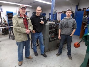 Former PHS shop teacher, Bill Neumann, current shop teacher, Dave Owens, and Sophomore shop student, Sebastian Davis stand next to the lathe machine in the high school shop. Photo/Angela Denning