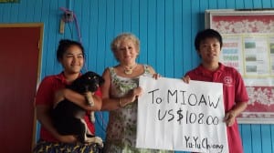 Yuyu Chiang (holding check) a MIOAW intern, held a fundraiser at Coop School by holding a movie night and selling popcorn. Patsy Peji Glad, Mioaw Majuro’s Secretary holds the school mascot Ralik. MIOAW founder, Lora Lee Mason stands in the middle. Photo courtesy of Lora Lee Mason
