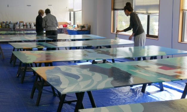 Volunteers finishing up repainting “Our Town” mural