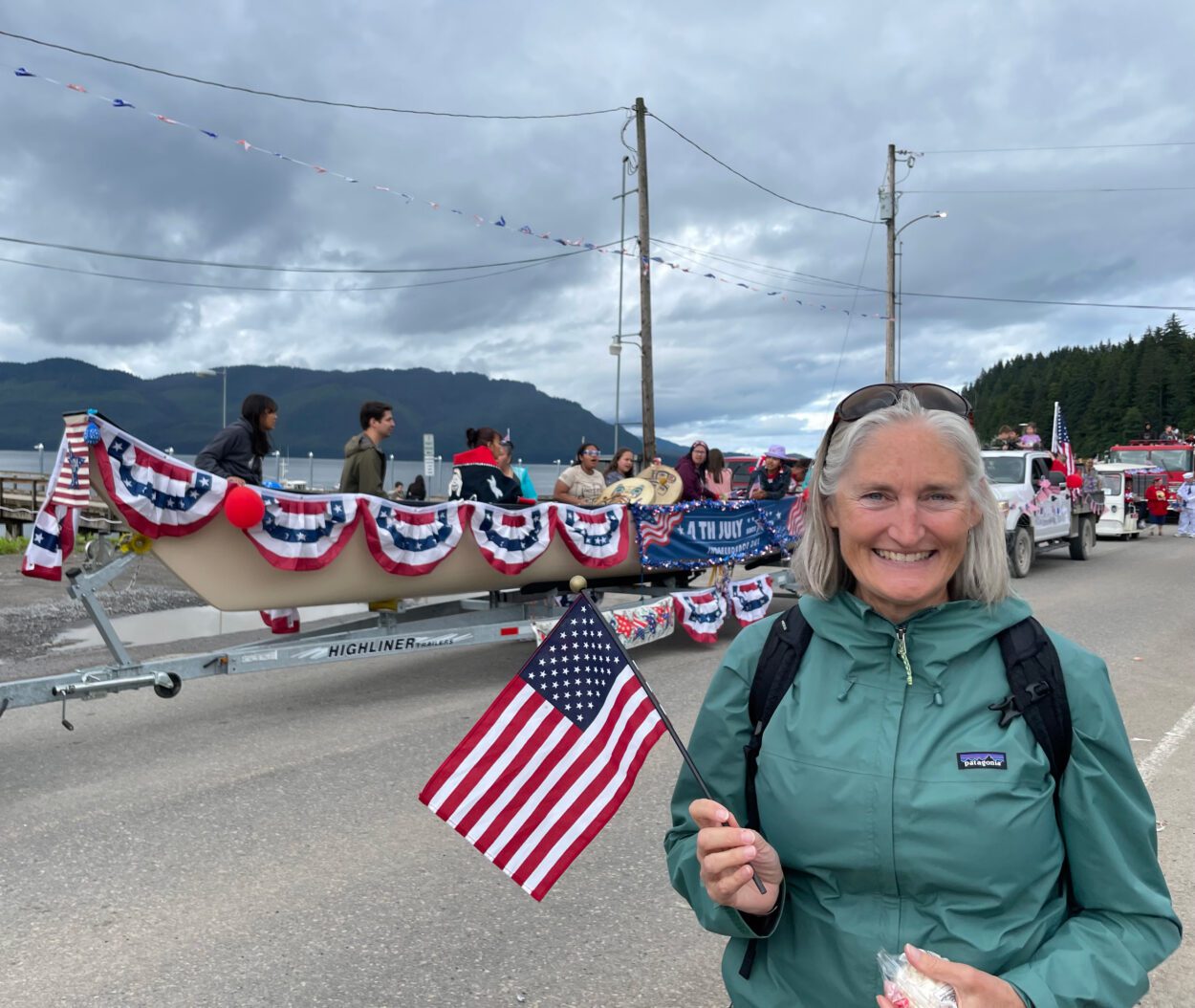 Rebecca Himschoot standing in front of a parade float. She is waving an American flag.